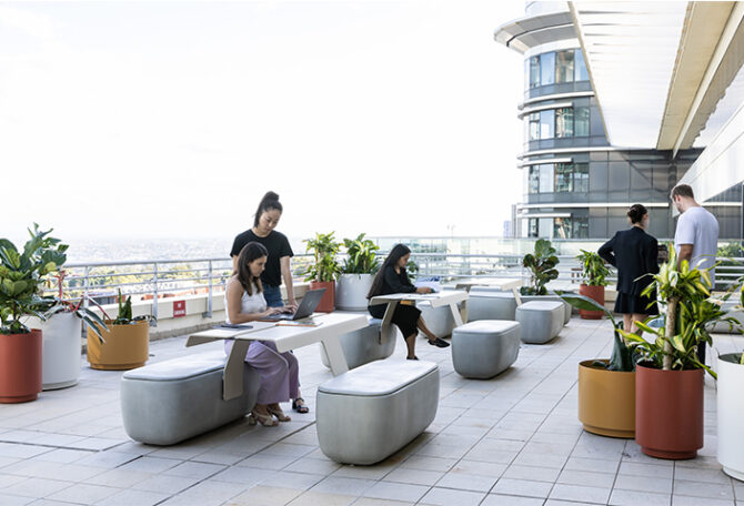 People working on rooftop balcony, sitting on outdoor furniture